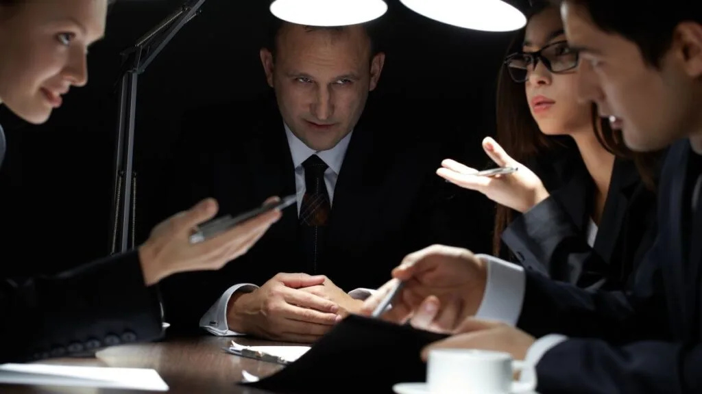 Group of healthcare professionals in business attire having serious discussion around table under focused lighting