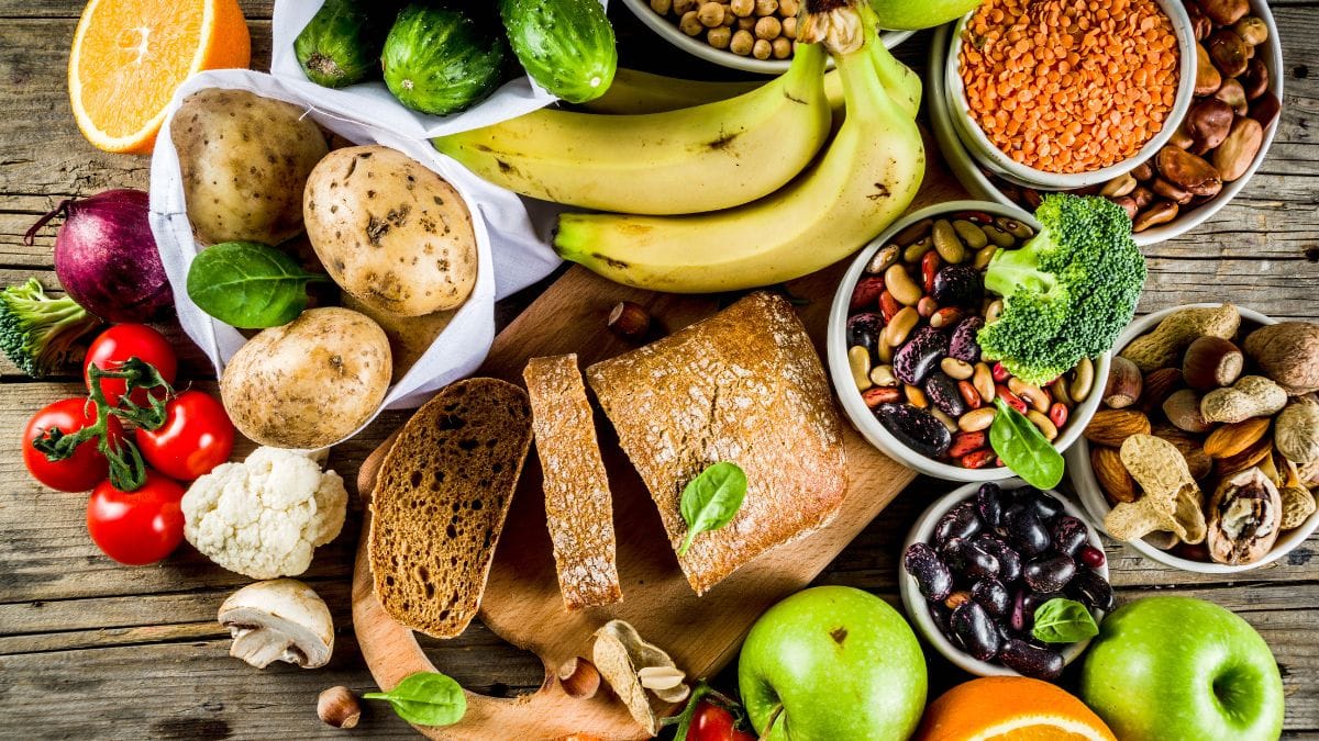 Rustic wooden surface with fresh produce including broccoli, Brussels sprouts, beans and whole grains