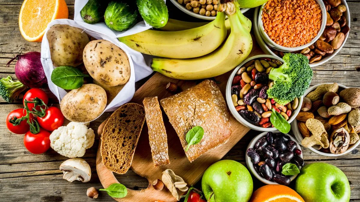 Rustic wooden surface with fresh produce including broccoli, Brussels sprouts, beans and whole grains